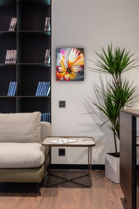 butterfly painting besides bookshelf in sitting area